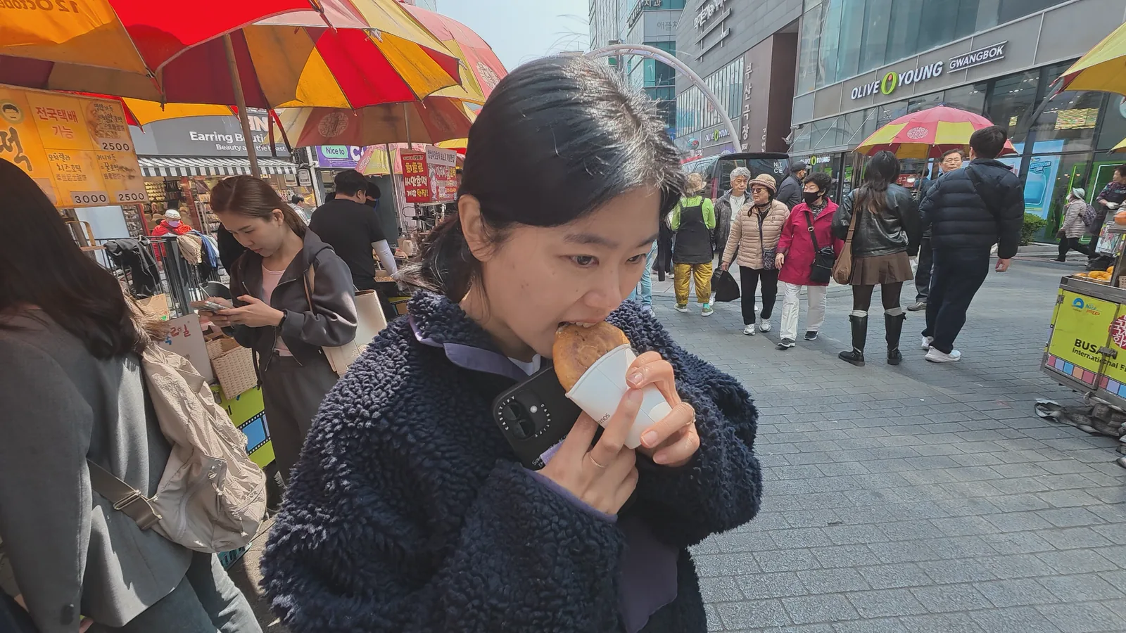 Traveler eating Korean street food in the Nampo-dong area of Busan