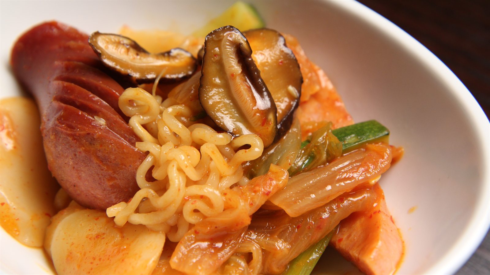 Budae jjigae with sausage, noodles, kimchi, and mushrooms in a bowl
