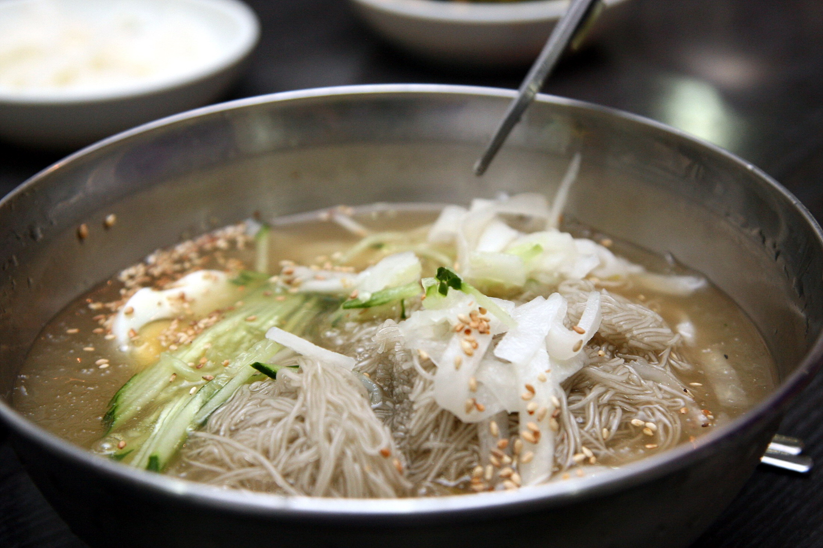 A bowl of mul naengmyeon with cold broth and sliced toppings