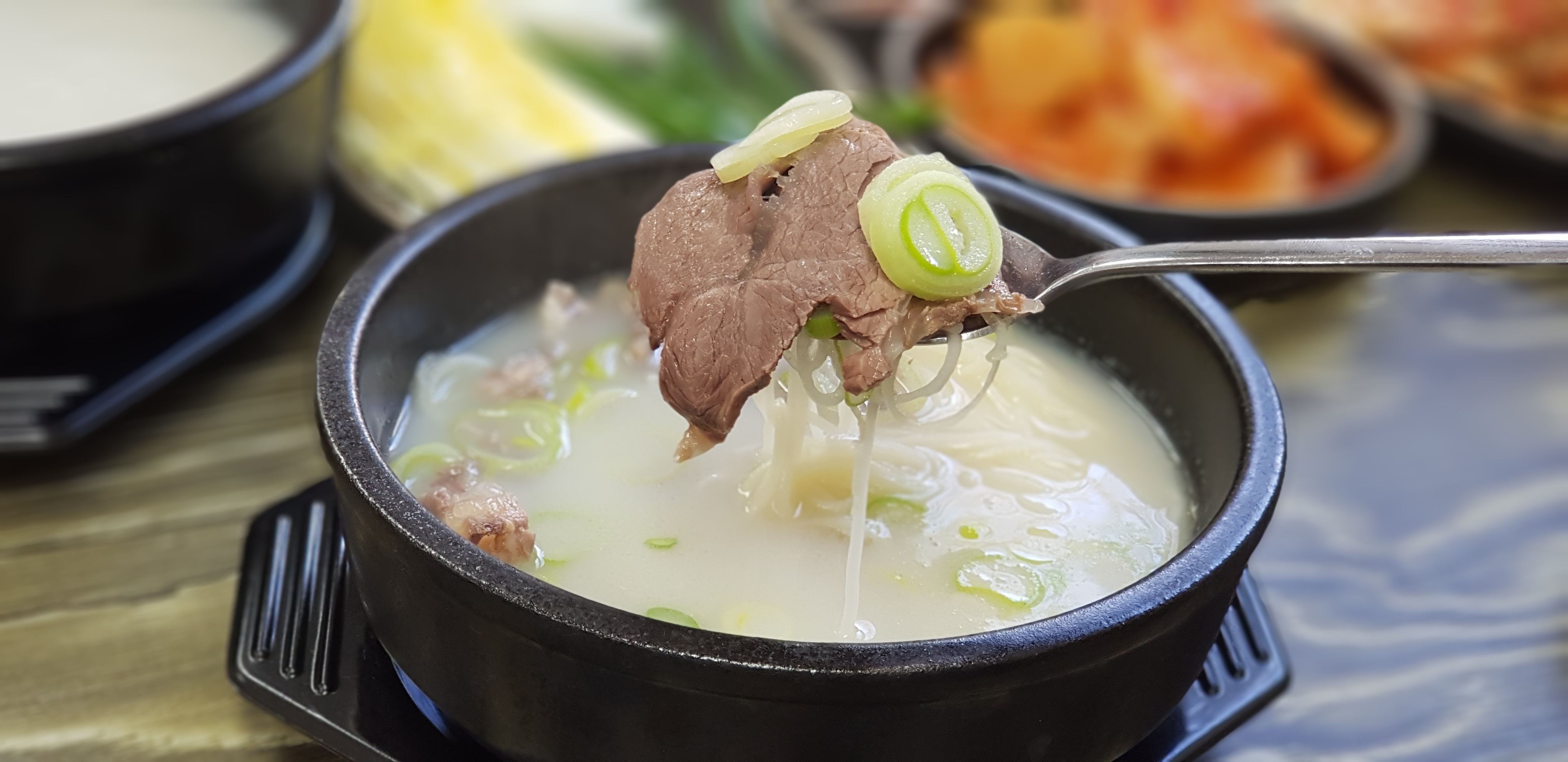 A bowl of seolleongtang with rice and side dishes