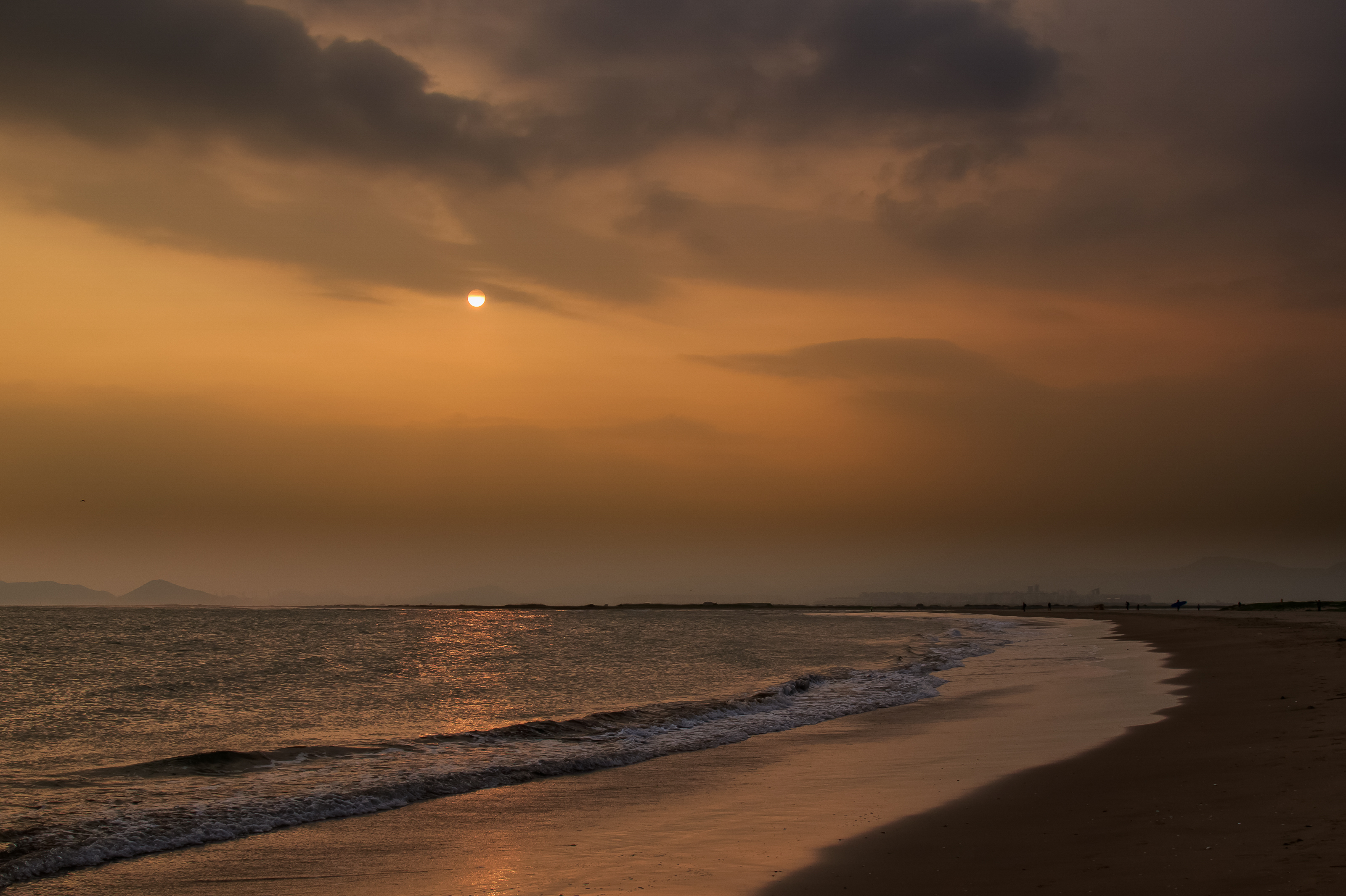 Sunset over the sea and sandy shoreline at Dadaepo Beach in Busan