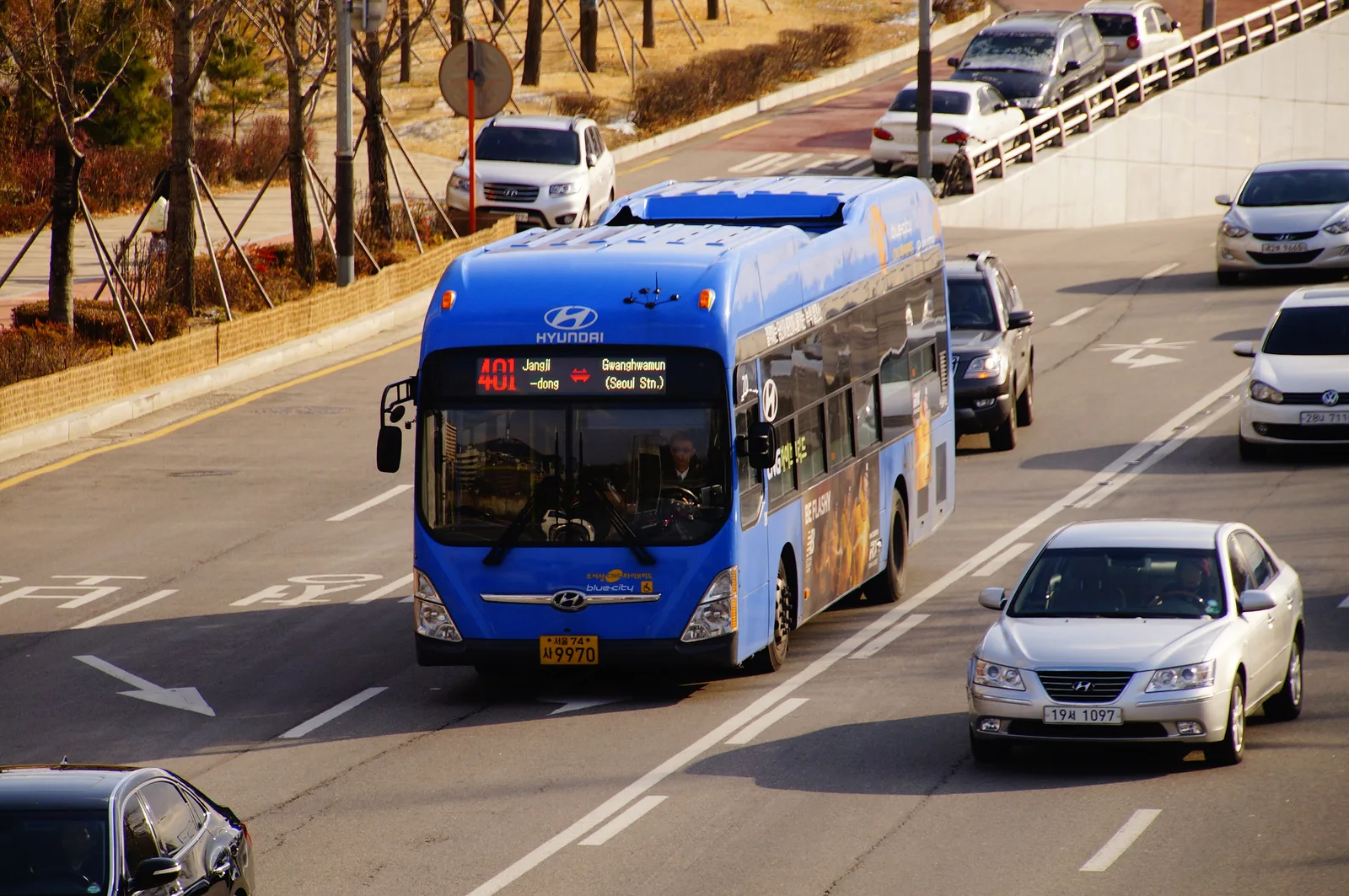 A blue Seoul route 401 city bus traveling on a multilane road