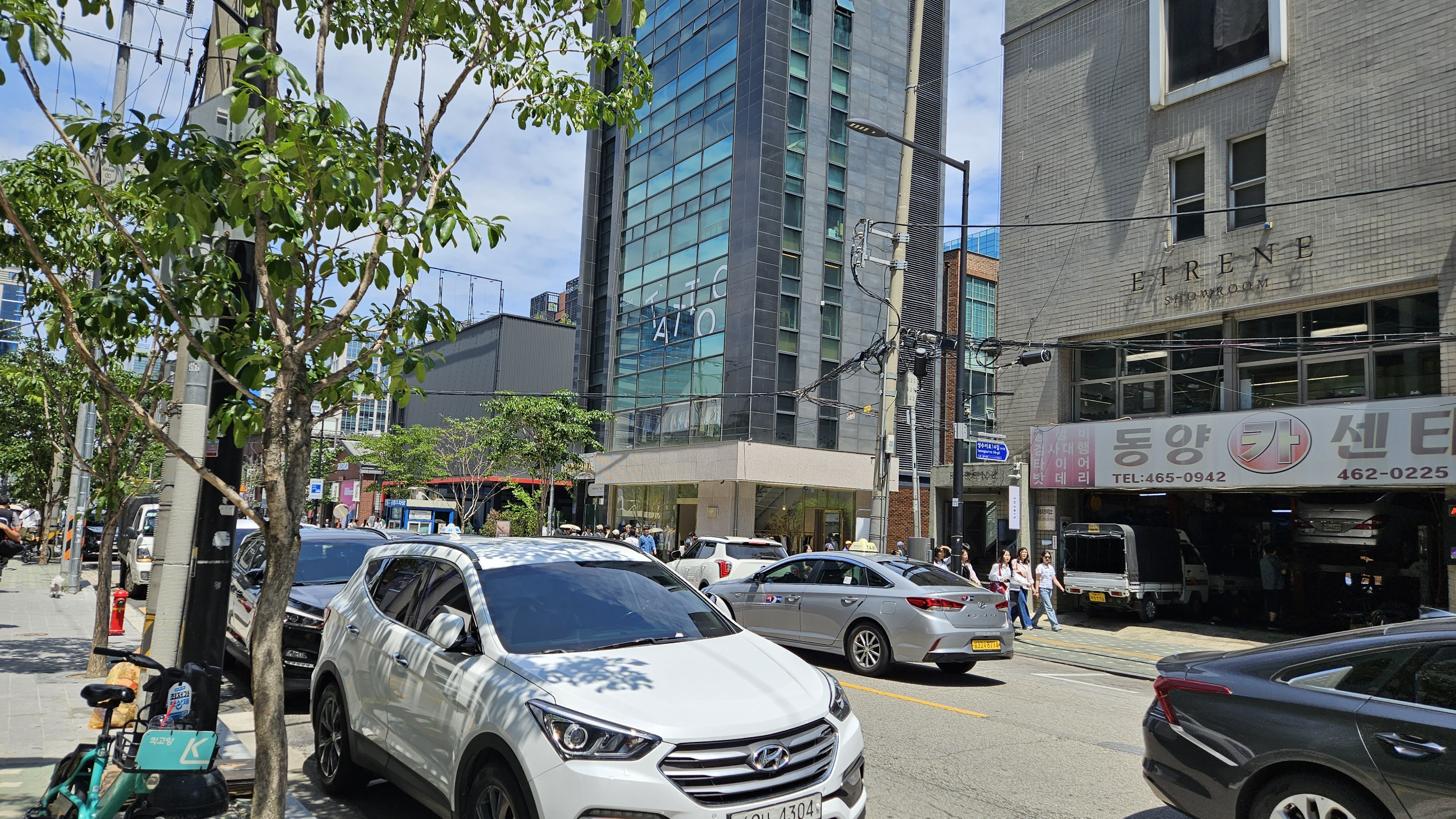 Street in Seongsu-dong with modern storefronts, cars, and pedestrians