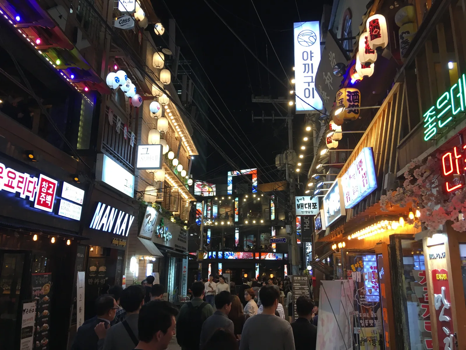 Night street scene in Seomyeon, Busan with illuminated signs and pedestrians.