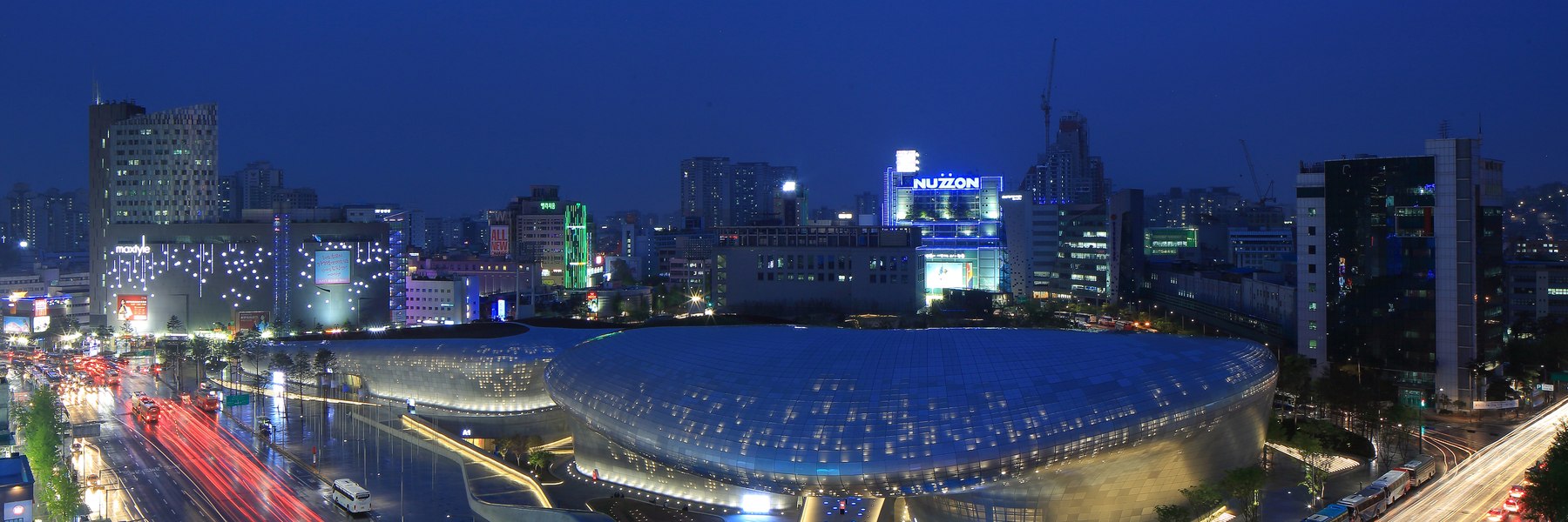 Curved exterior of Dongdaemun Design Plaza illuminated at night