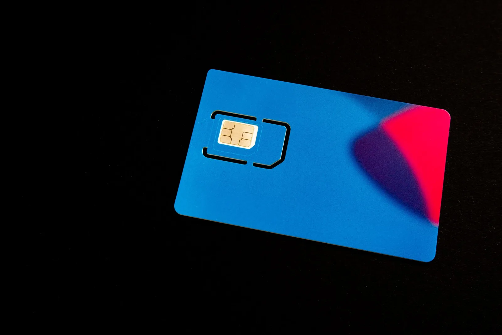 A physical SIM card mounted in a blue holder on a dark background