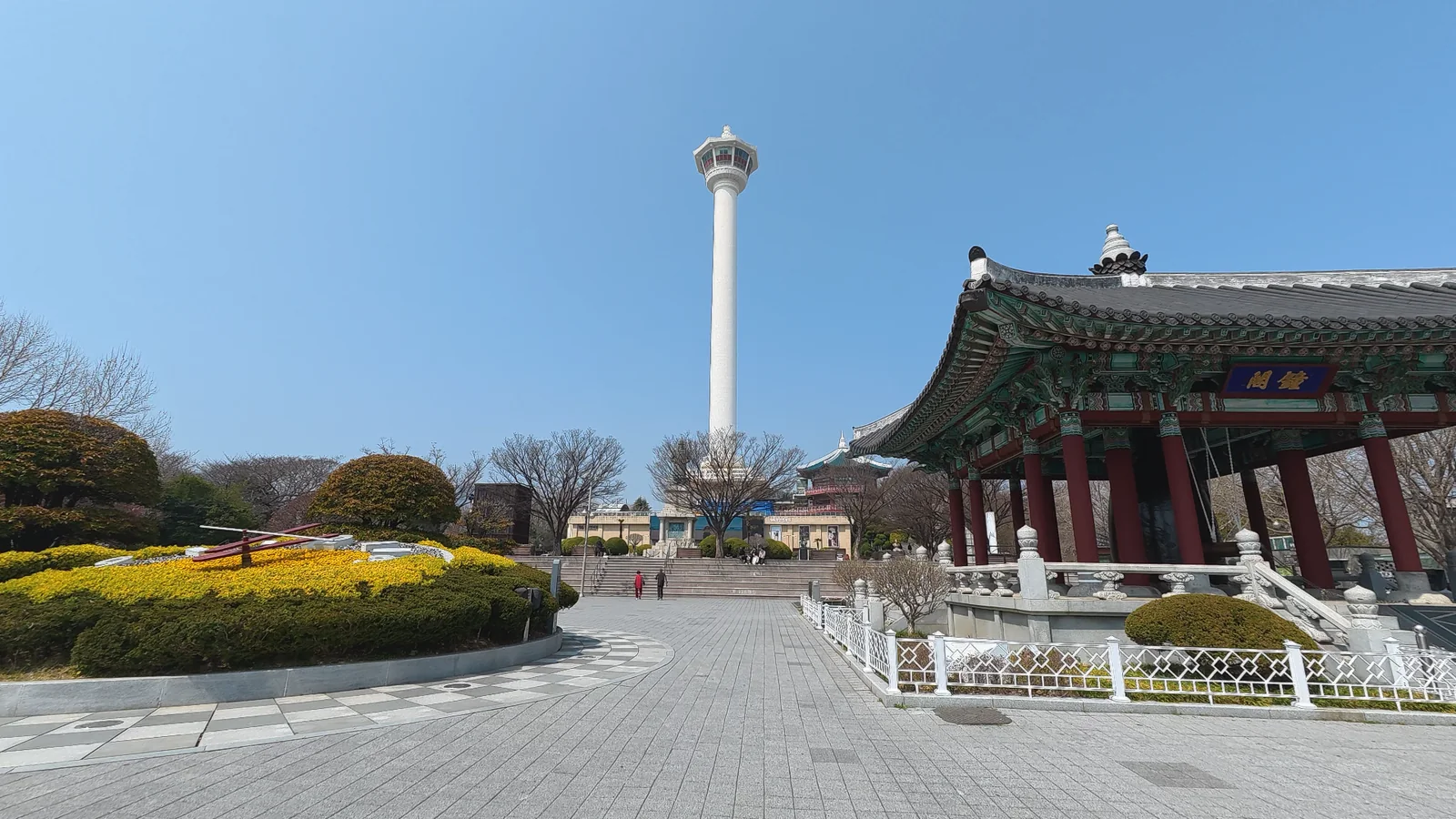 Yongdusan Park in Busan with Busan Tower and a traditional pavilion under a clear blue sky.