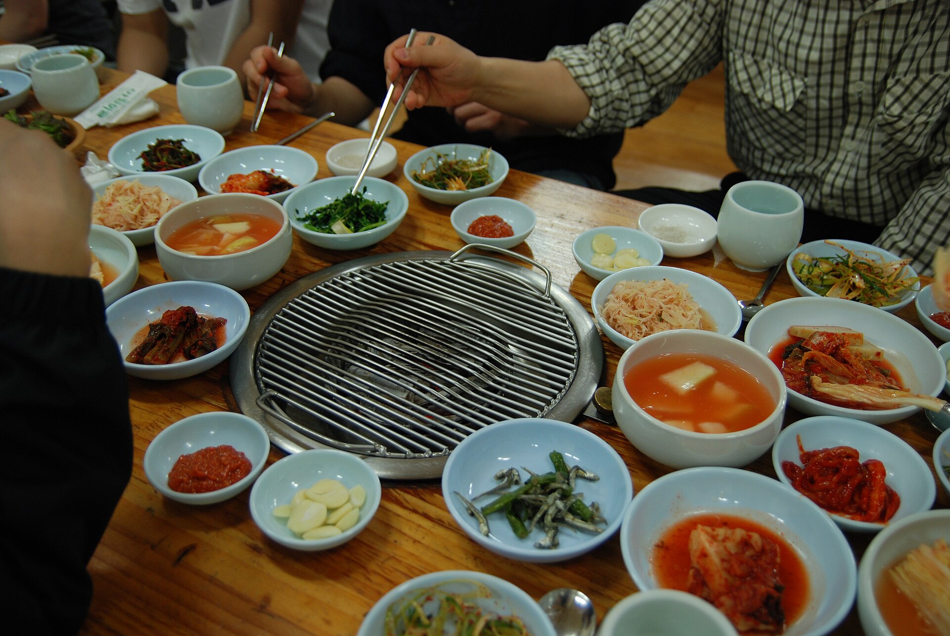 Korean BBQ grill and banchan side dishes on a restaurant table