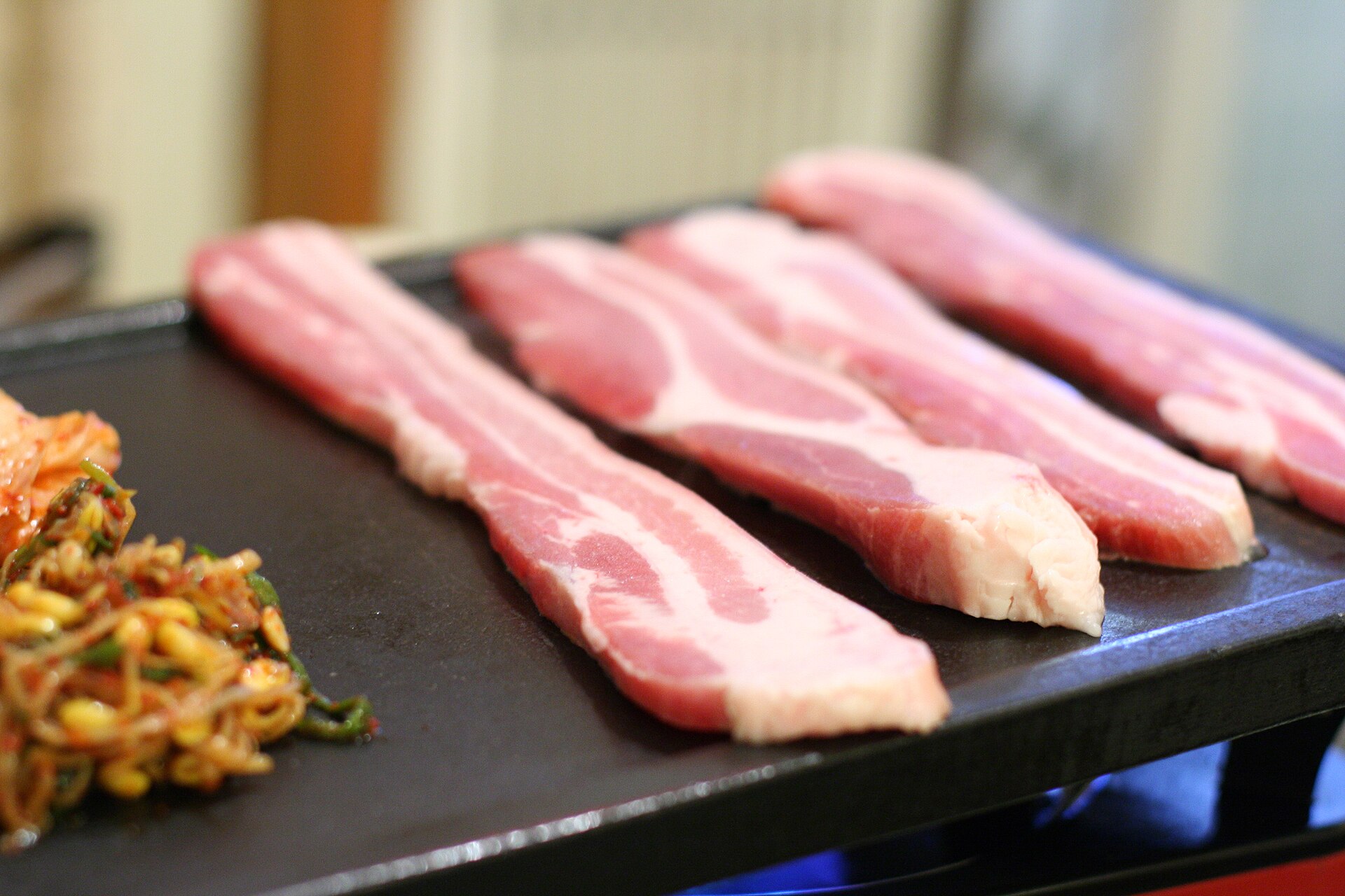 Samgyeopsal pork belly grilling on a Korean BBQ table