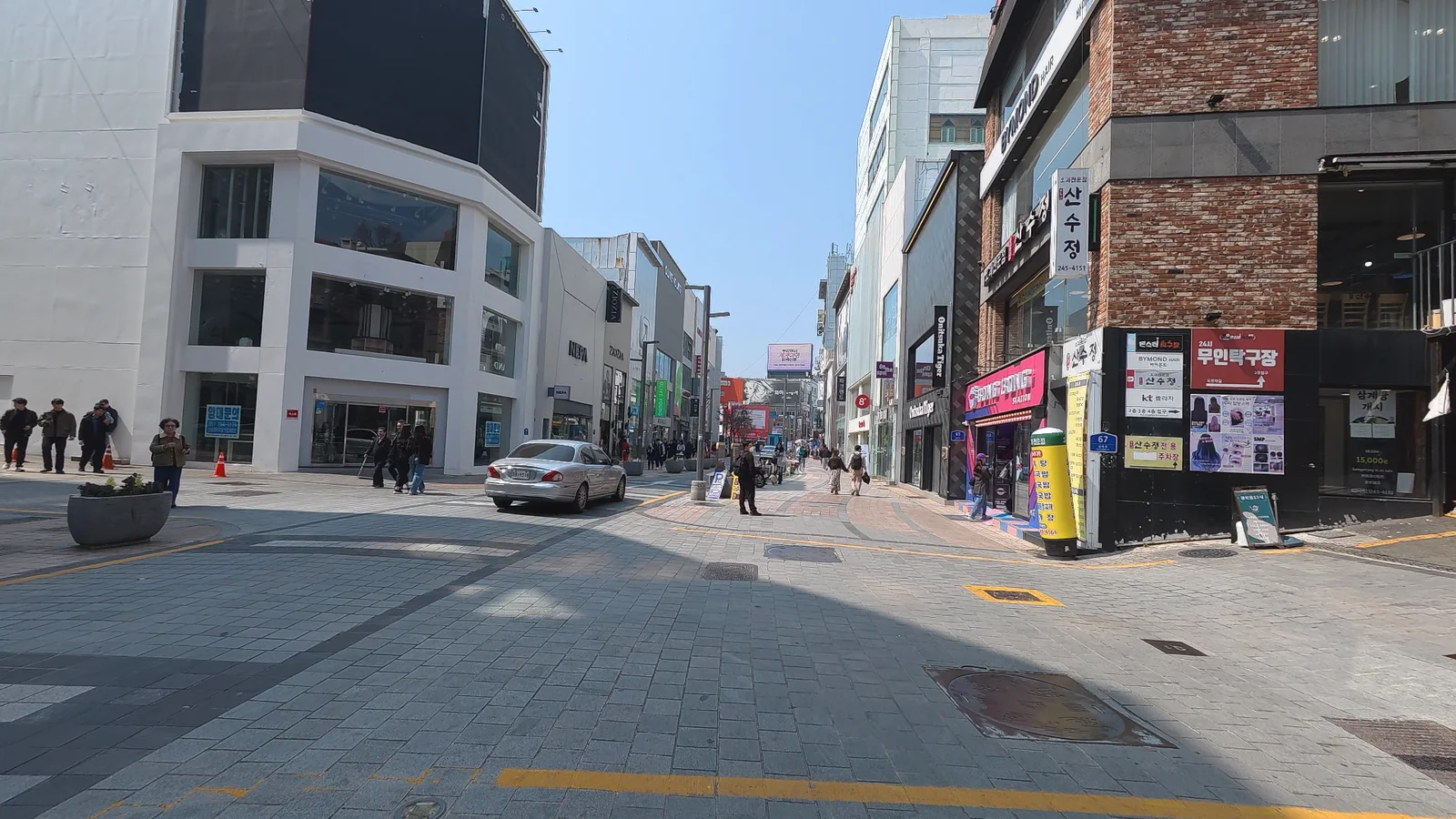A pedestrian street in Nampo-dong, Busan, lined with shops, restaurants, and signs on a clear day.