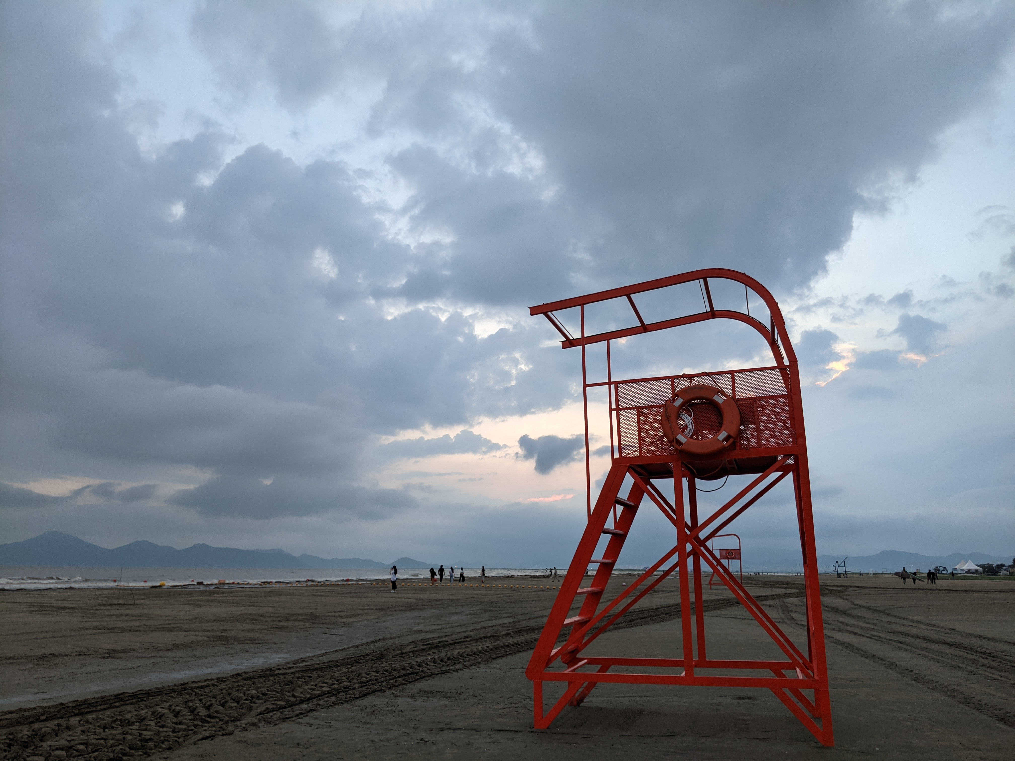 A red lifeguard chair on Dadaepo Beach beneath an evening sky